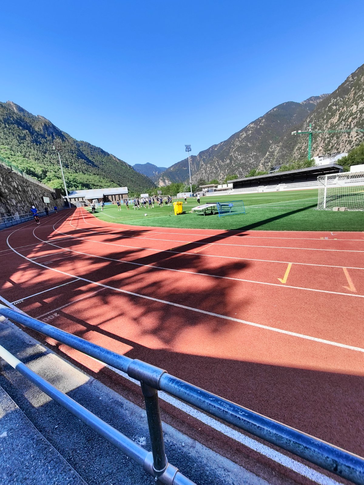 Pista d'atletisme i camp de futbol en un estadi esportiu envoltat de muntanyes